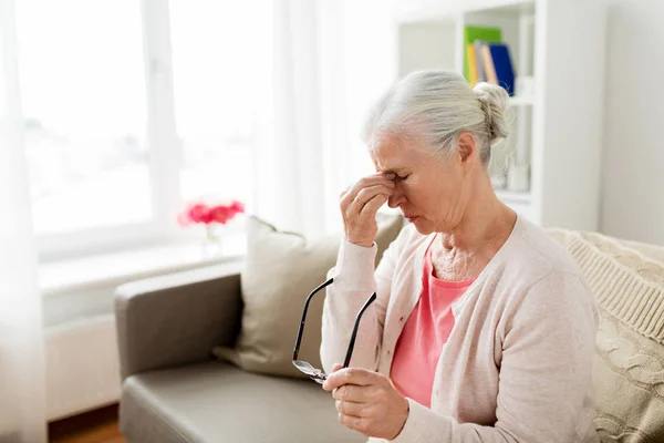 Mulher idosa com óculos tendo dor de cabeça em casa — Fotografia de Stock