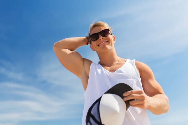 Sorridente giovane uomo in occhiali da sole sopra il cielo blu — Foto Stock