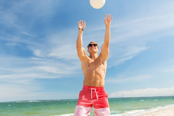 Młody człowiek z piłką gra w siatkówkę na plaży — Zdjęcie stockowe