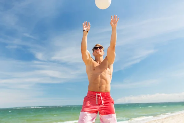 Junger Mann mit Ball spielt Volleyball am Strand — Stockfoto