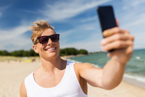 Hombre con teléfono inteligente tomando selfie en la playa de verano — Foto de Stock