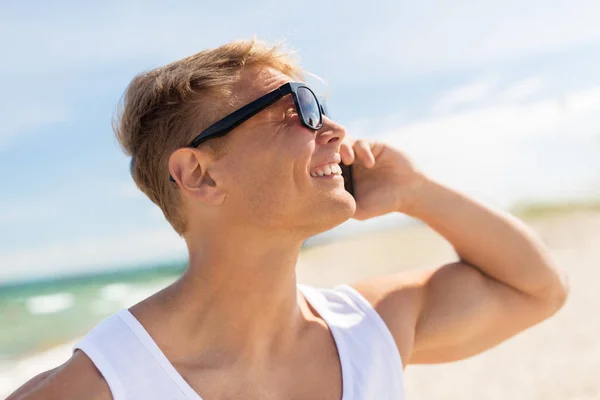Gülümseyen adam Smartphone'da yaz sahilde arıyor — Stok fotoğraf