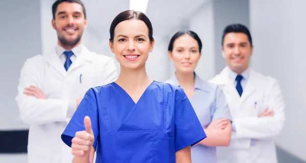 Medics or doctors at hospital showing thumbs up — Stock Photo, Image
