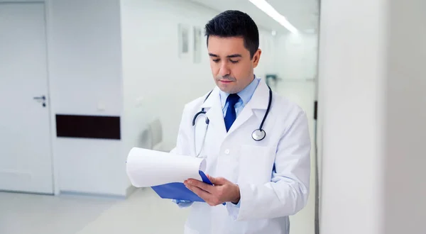 Doctor writing to clipboard at hospital — Stock Photo, Image