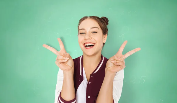Student szczęśliwy dziewczyna pokazuje znak pokoju nad zielony — Zdjęcie stockowe