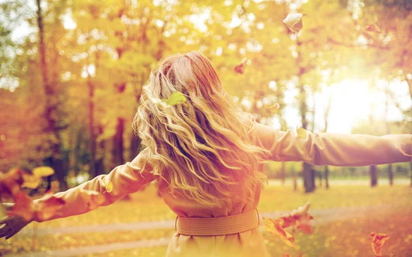 Щаслива жінка розважається з листям в осінньому парку — стокове фото