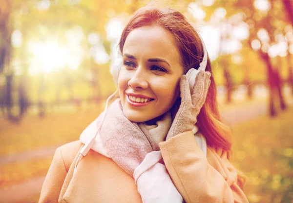 Mulher em fones de ouvido ouvir música no parque de outono — Fotografia de Stock