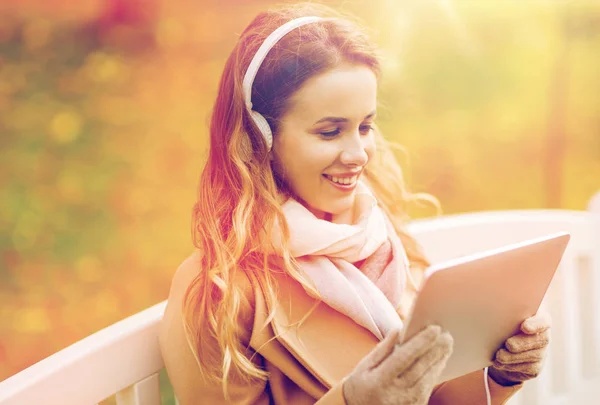 Mujer con tablet PC y auriculares en el parque de otoño — Foto de Stock