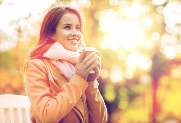 Fröhliche junge Frau trinkt Kaffee im Herbstpark — Stockfoto