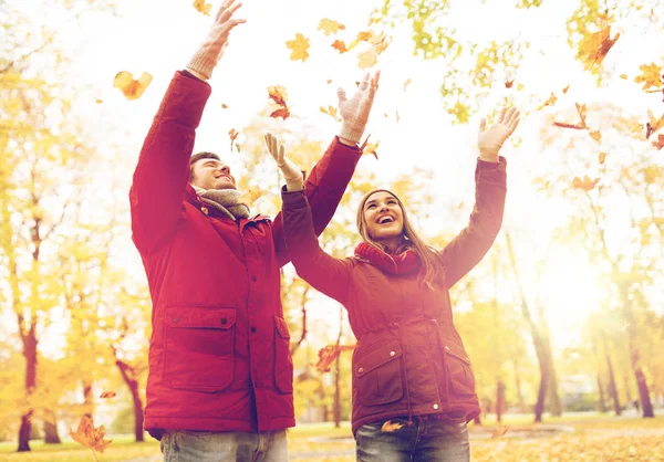 Happy νεαρό ζευγάρι ρίχνουν φθινόπωρο αφήνει στο πάρκο Royalty Free Φωτογραφίες Αρχείου