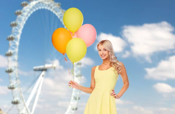 Gelukkige vrouw met lucht ballonnen over reuzenrad — Stockfoto