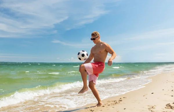Jovem com bola jogando futebol na praia — Fotografia de Stock