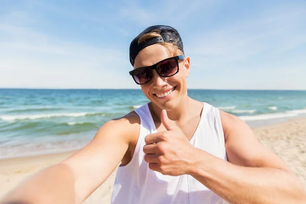 Homem de óculos de sol tomando selfie na praia de verão — Fotografia de Stock