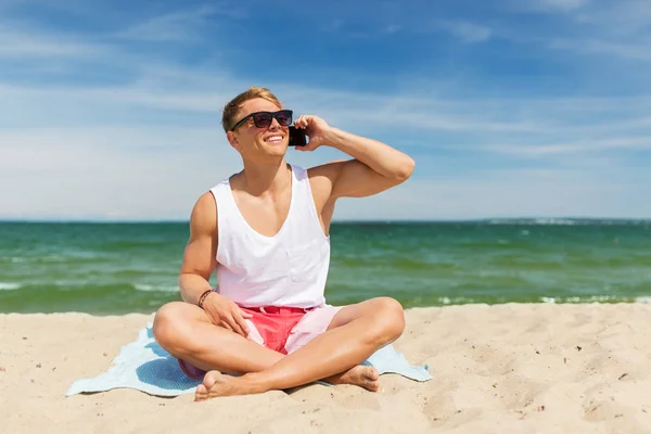 Smiling man calling on smartphone on summer beach — Stock Photo, Image
