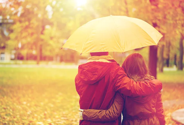 Casal feliz com guarda-chuva andando no parque de outono — Fotografia de Stock