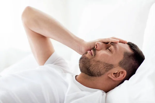 Homme au lit à la maison souffrant de maux de tête — Photo