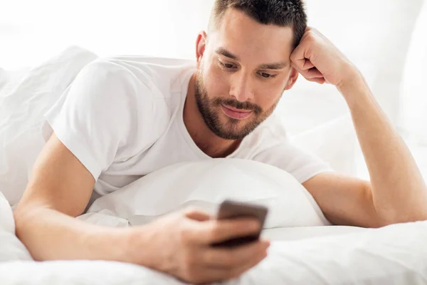 Zár-megjelöl-ból smartphone az ágyban az ember reggel — Stock Fotó
