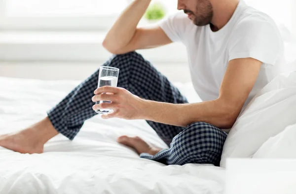 Hombre en la cama con vaso de agua en casa —  Fotos de Stock