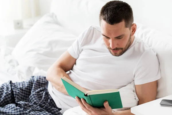 Uomo lettura libro a letto a casa — Foto Stock