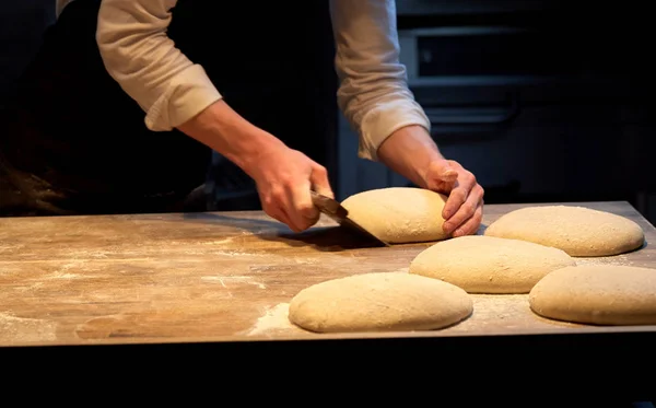 Пекарь порции теста со скамейкой резак в пекарне — стоковое фото