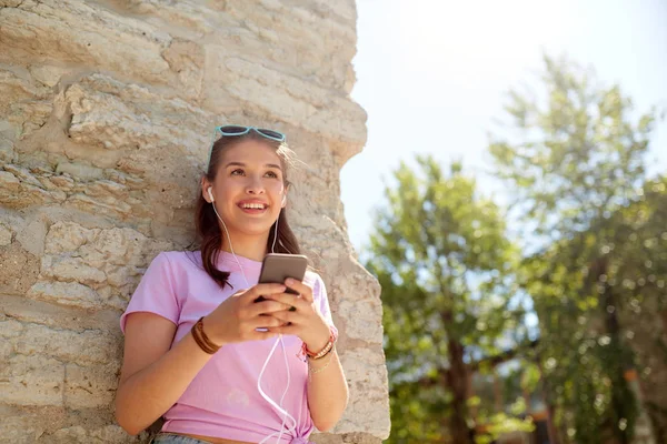 Feliz joven con teléfono inteligente y auriculares — Foto de Stock