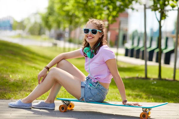 Menina adolescente feliz com fones de ouvido e longboard — Fotografia de Stock