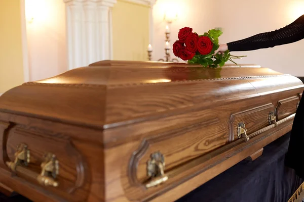 Mulher com rosas vermelhas e caixão no funeral — Fotografia de Stock