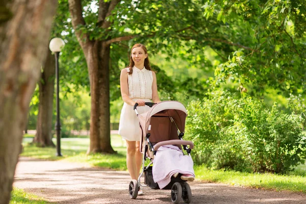 Ibu bahagia dengan anak di kereta bayi di taman musim panas — Stok Foto