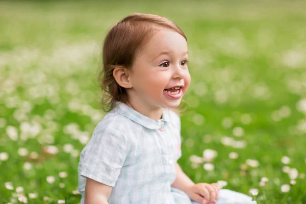 Happy baby girl on green summer field — Stock Photo, Image