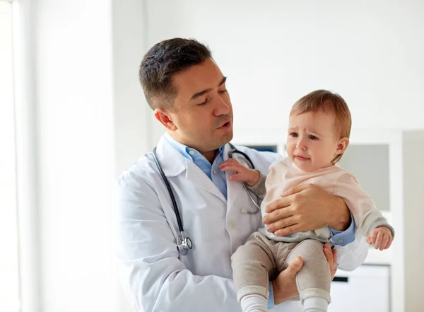 Доктор держит плачущего ребенка в клинике — стоковое фото