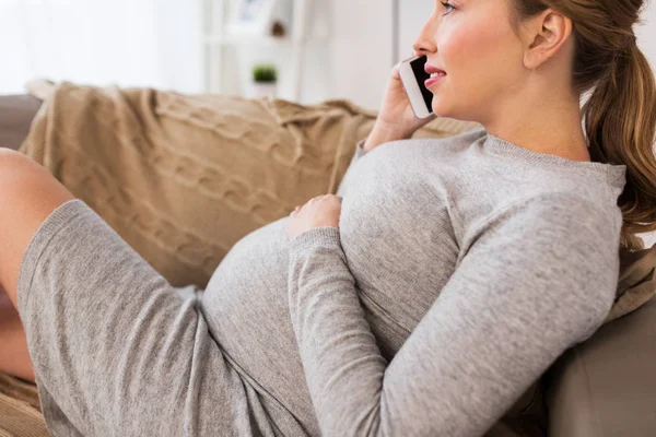 Счастливая беременная женщина звонит на смартфон дома — стоковое фото