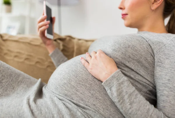 Felice donna incinta con smartphone a casa — Foto Stock