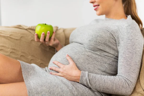 Glückliche schwangere Frau isst grünen Apfel zu Hause — Stockfoto