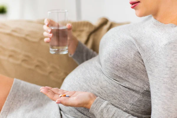 Primo piano della donna incinta con pillole a casa — Foto Stock