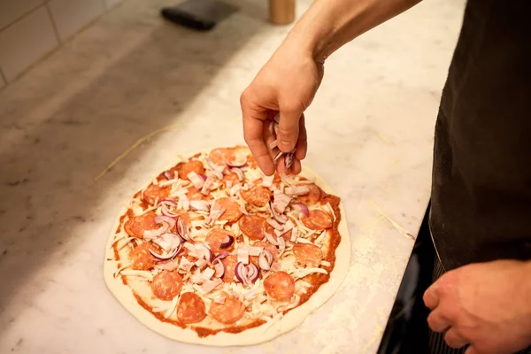 Pizzacı Pizza'da salam ekleyerek soğan yemek — Stok fotoğraf