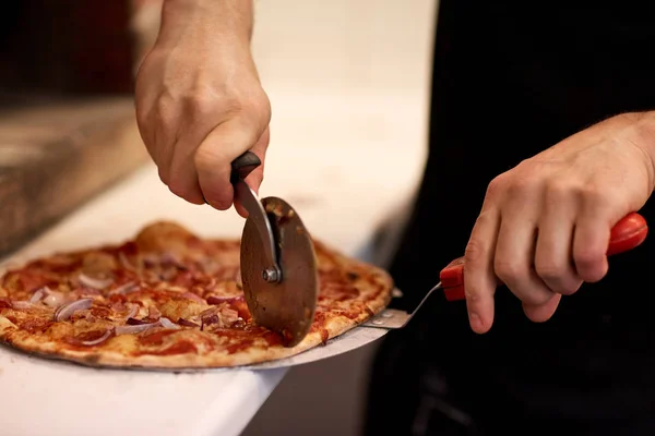 Kesme pizza pizzacı, parçalara el yemek — Stok fotoğraf