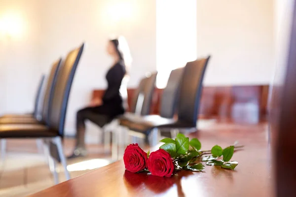 Red roses and woman crying at funeral in church — Stock Photo, Image