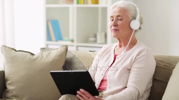 Senior Kvinna med TabletPC och hörlurar hemma — Stockvideo