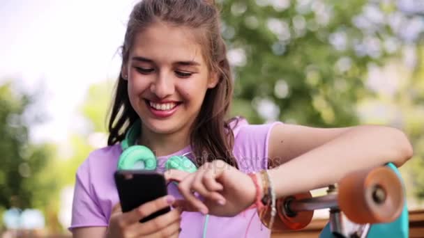 Happy teenage girl with smartphone and longboard — Stock Video