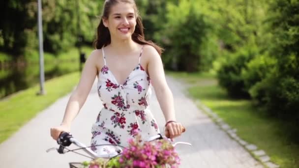Happy young woman riding bicycle in summer park — Stock Video