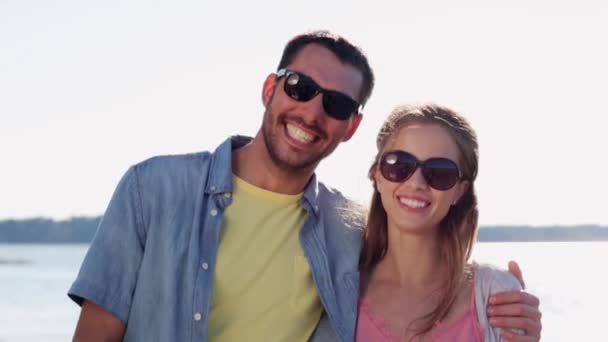 Happy couple in sunglasses hugging over sea — Stock Video