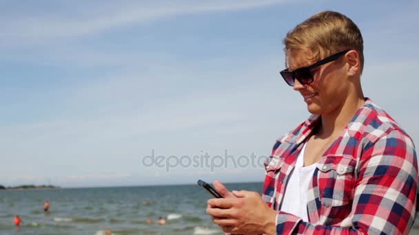 Мужчина со смартфоном делает селфи на летнем пляже — стоковое видео