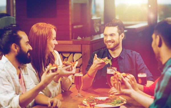 Vrienden eten pizza met bier in restaurant — Stockfoto