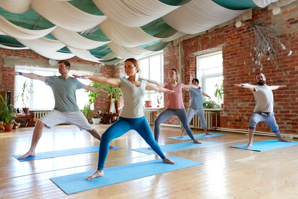 Groep van mensen doen yoga krijger pose in studio — Stockfoto