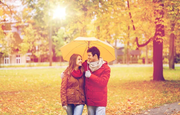 Pareja sonriente con paraguas en el parque de otoño — Foto de Stock