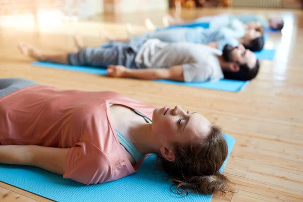 Kvinna med grupp människor som gör yoga på studio — Stockfoto