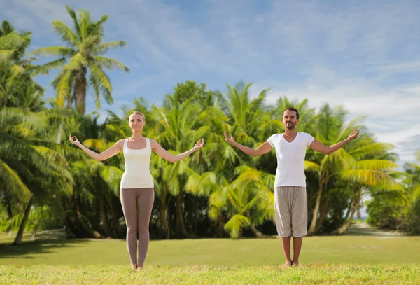 Gelukkige paar maken van yoga oefeningen op strand — Stockfoto