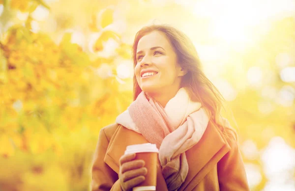 幸福的年轻女人，在秋天的公园里喝咖啡 — 图库照片