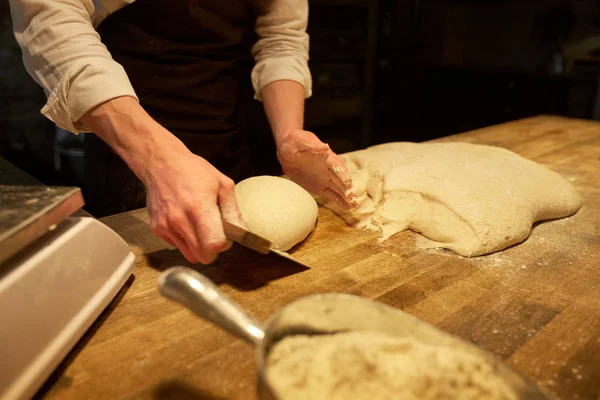 Baker portioning dough with bench cutter at bakery — Stock Photo, Image