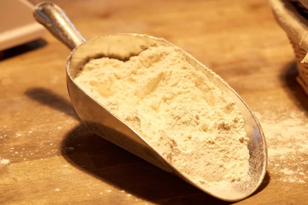 Harina en cucharada de panadería en mesa de cocina de madera — Foto de Stock